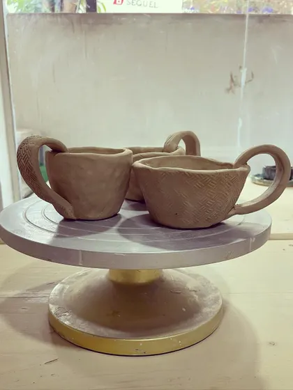 A set of three charming, rustic cups, each with its own unique texture, all made using the hand-building pinch method.