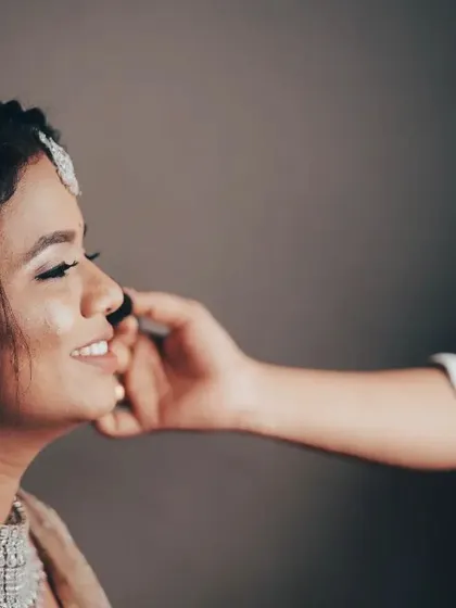 A gentle moment during the makeup application process, capturing the bride's happy and relaxed mood.