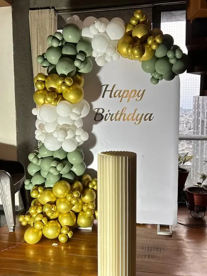This simple backdrop with a balloon half-arch in olive green, gold, and white is perfect for smaller spaces. It provides a beautiful spot for photos without overwhelming the room.