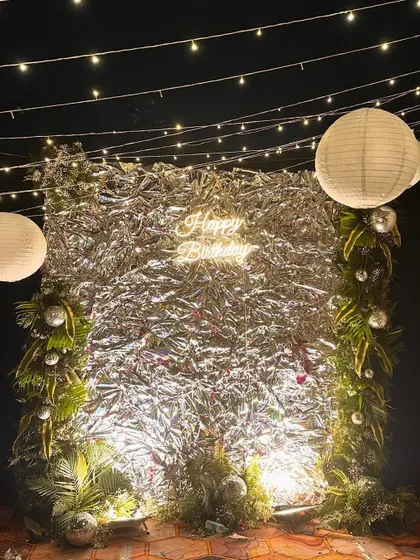 A shimmery and fun birthday backdrop we created for a rooftop party. The silver foil curtain, neon sign, and paper lanterns created a festive and glamorous photo corner.