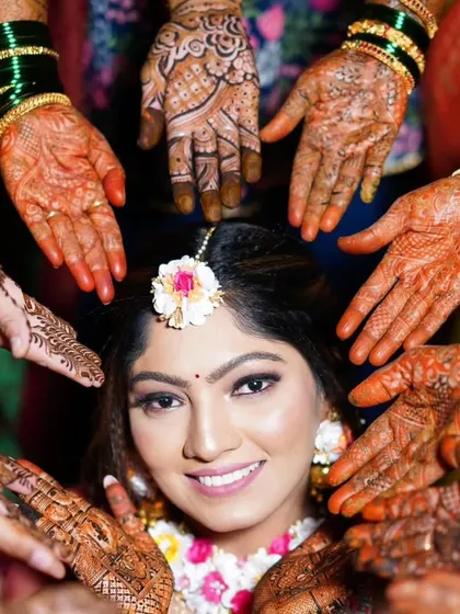 A creative shot of a bride surrounded by the mehandi-adorned hands of her friends and family. A beautiful symbol of love and support.