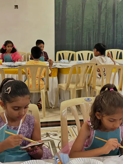 A wider view of the party in action. Kids are seated and engaged in their painting, showing how an art activity can be a calm yet exciting focus for a birthday celebration.