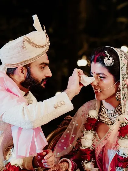 A playful and caring moment where the groom helps the bride, showcasing their partnership.