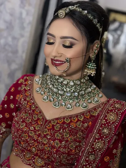 A close-up on the eyes. This image highlights the golden glitter eyeshadow and bold red lip, a classic combination for a traditional Indian bride in a red lehenga.