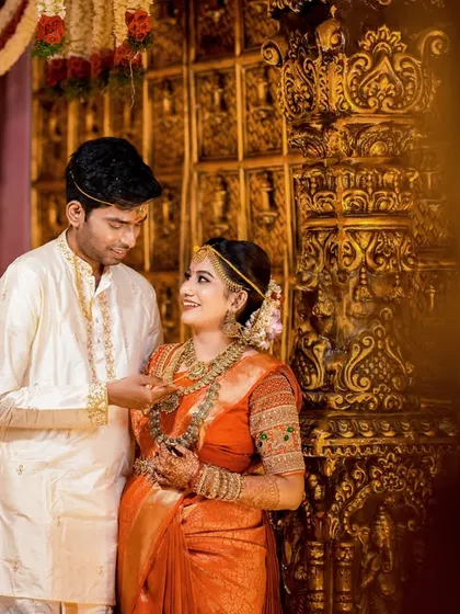 The groom gently adjusts the bride's jewelry, a small, intimate gesture amidst the grand setting.
