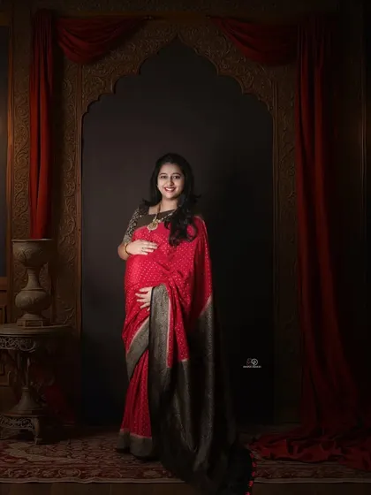 There is nothing more graceful than a maternity portrait in a saree. This regal studio setup with rich, dark colors and elegant lighting creates a timeless and culturally rich image.