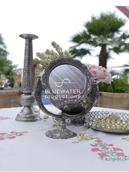 An ornate silver mirror and candle stand add a touch of vintage elegance to a tabletop arrangement.