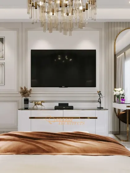 The media wall in this bedroom is a statement piece, featuring a large TV, a stunning chandelier, and a sleek white console with gold trim.