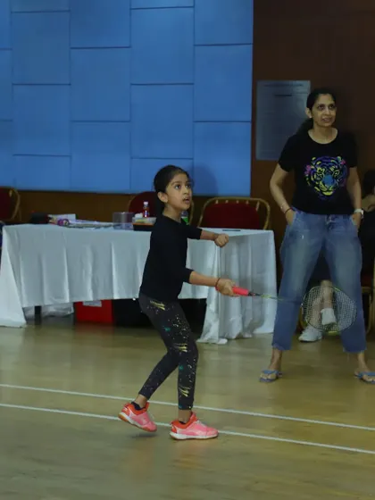 A young girl lunges forward for a net shot, demonstrating the agility and footwork she has developed through our training.