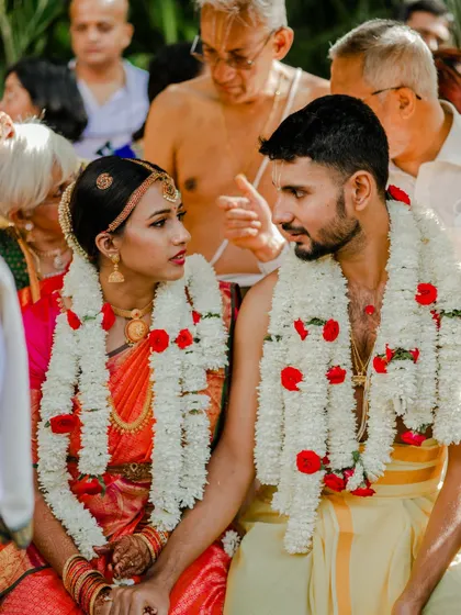 A couple shares an intimate gaze during their wedding ceremony, adorned with beautiful jasmine garlands.
