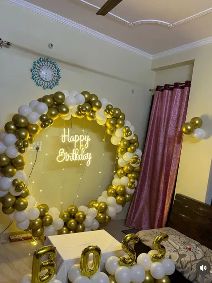 A classic birthday decoration for a "Boss" with a gold and white balloon ring. The setup includes a neon sign and the name spelled out with balloon pillars.