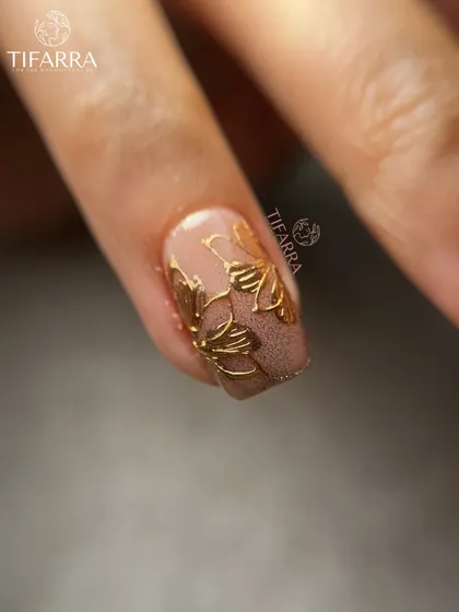 A close-up of our hand-drawn gold floral art on a matte, textured brown base, showcasing the versatility of our designs.