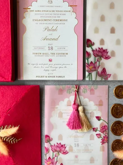 The complete P&A engagement invitation set, showcasing the main card with its elegant jharokha-style frame and the accompanying vellum wrap with lotus illustrations.
