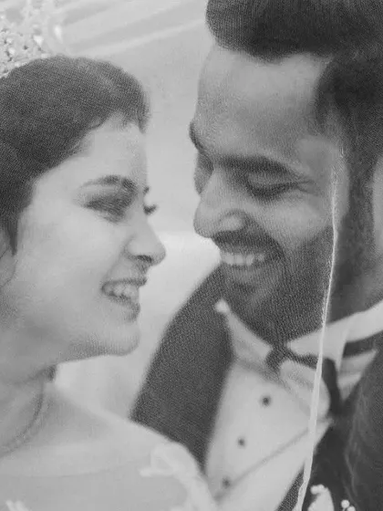An intimate black and white portrait of the couple under the veil. The genuine smiles and close framing make this a beautifully romantic shot.