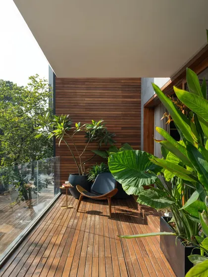 A wooden-decked balcony at Timber Edge, designed as a private outdoor retreat with lush plants and comfortable seating.