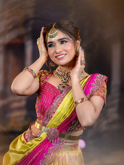 The model poses playfully, showing off her full attire. The combination of pink and yellow is a classic choice for Indian festivities.