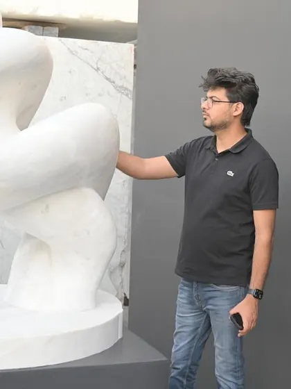 Kunal examining the smooth, curved lines of a contemporary marble art piece.