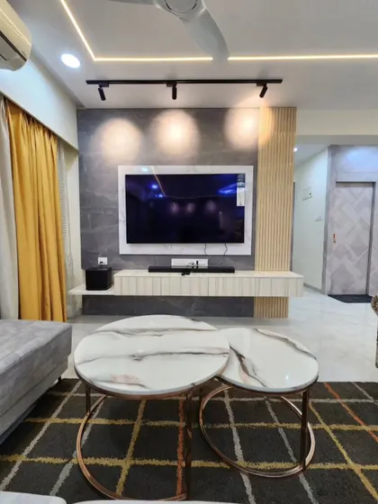 A wider shot of the living room, showing the TV unit, nesting coffee tables, and the overall color scheme.
