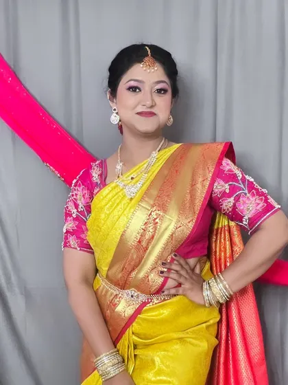 Posing with confidence, this client is ready for her family event. The makeup is kept elegant and fresh to complement her bright saree and traditional jewelry.