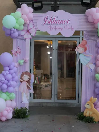 The entrance to the bunny-themed first birthday party, with a beautiful balloon arch and a photo milestone board celebrating the baby's first year.