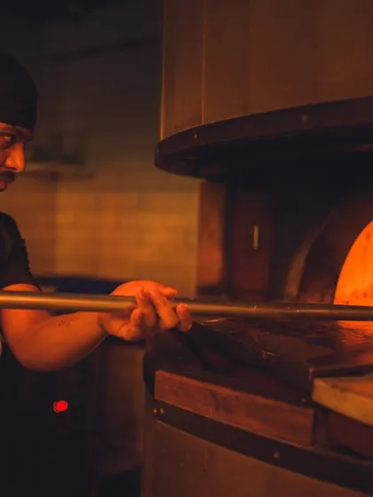 Our pizzaiolo in their element, managing the intense heat of the wood-fired oven. This is where skill and passion come together to create your perfect pizza.