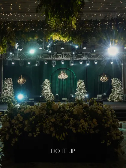 The sangeet stage was designed with a dramatic emerald green velvet curtain and classic crystal chandeliers. The floral installations on the stage floor added a layer of softness and texture.