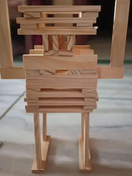 A friendly robot built from geometric shapes. This creation demonstrates how linear planks can be arranged in a non-linear way to form a recognizable character, blending artistic creativity with structural engineering.