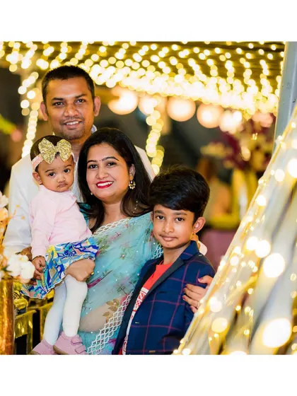A beautiful family portrait taken amidst the warm glow of decorative lights at a birthday party. We use creative lighting to make your family photos magical.
