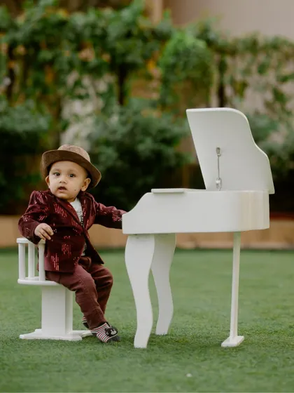 A duplicate of image 22, this stylish portrait features a baby boy in a suit and hat at a miniature white piano.