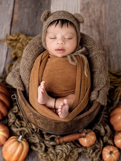 A perfect overhead shot of the autumn theme, with the baby nestled in a bowl and surrounded by pumpkins of all sizes.