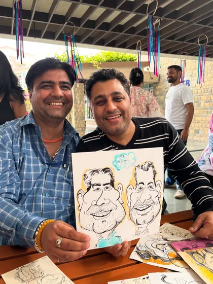 Two friends sharing a laugh and a caricature at the ISB alumni event.