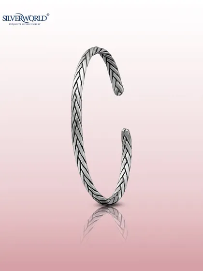 This is our classic braided silver kada, an open-cuff bangle with an oxidized finish. The woven texture gives it a timeless, rugged appeal that is both sophisticated and easy to wear.