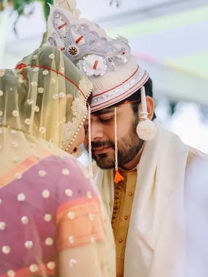 Another angle of this intimate moment during the pheras. The traditional Bengali 'topor' worn by the groom adds a beautiful cultural detail to the photograph.