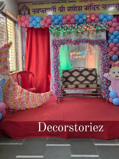 A beautiful setup for a traditional naming ceremony or 'Barsa'. The centerpiece is a decorated jhula (cradle) on a staged platform, framed by balloons and adorable baby cutouts, creating a memorable spot for this important occasion.