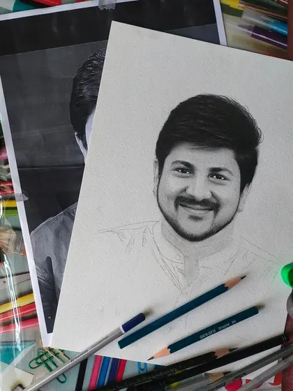 This flat lay shot shows a portrait in progress, surrounded by the tools of my trade. You can see the reference photo, my graphite pencils, an eraser, and a sharpener, all essential for my work.