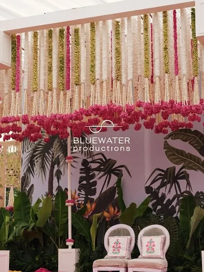 The main stage for a traditional Haldi, featuring a backdrop of banana leaves and a canopy of hanging floral strings.