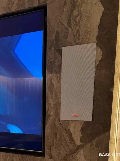 A close-up of a Starke Sound in-wall speaker, which sits nearly flush against the marble wall. This is the ideal solution for high-end sound that doesn't interfere with your interior design.