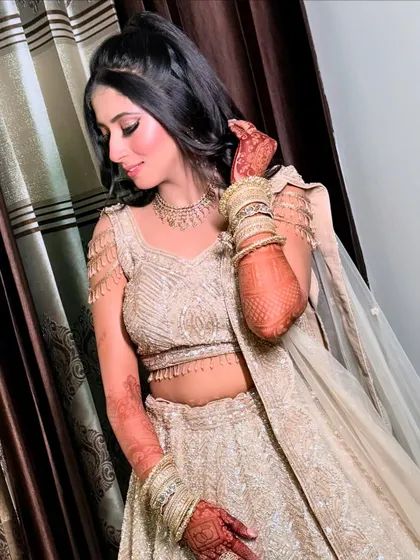 A graceful pose showing the intricate details of her lehenga's shoulder design and her perfectly styled hair.