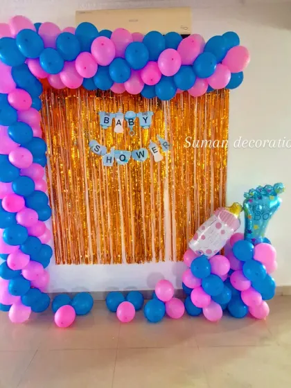 Another view of the pink and blue baby shower decoration, showing the foil balloon props of a baby bottle and foot.