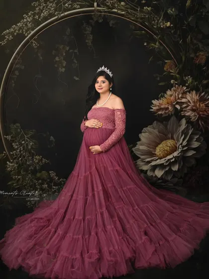 A fairytale portrait with a floral hoop. The mom-to-be, wearing a tiara and a beautiful mauve gown, looks like she stepped out of a storybook.