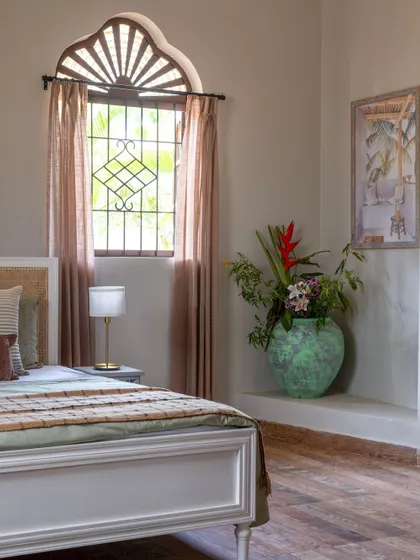 A bedroom from our Goan holiday villa project. The design features a classic bed, an antique-style window, and a large rustic vase, all contributing to a relaxed, vacation vibe.