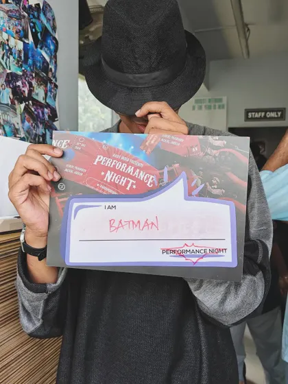 The excitement is real. One of our performers holding a sign that says "I AM BATMAN," capturing the fun and playful spirit of Performance Night.