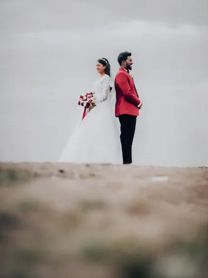 An artistic shot of the couple standing back-to-back on a sand dune. This creative composition tells a story and creates a memorable image.