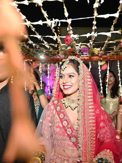 The bride's joyful entry under the 'phoolon ki chaadar', her smile radiant as she walks towards her new beginning.