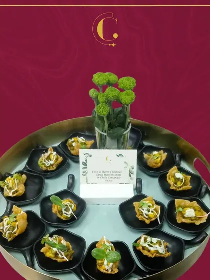 A tray of Corn & Water Chestnut Wontons, tossed in a zesty chilli coriander sauce. These appetizers offer a delightful combination of crunch, sweetness, and heat.