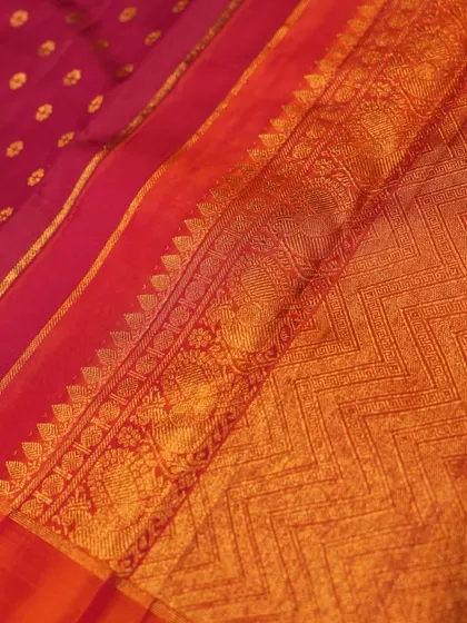 A detailed shot of a maroon Kanjivaram border, featuring a chevron (vanki) pattern alongside peacock motifs in gold zari.