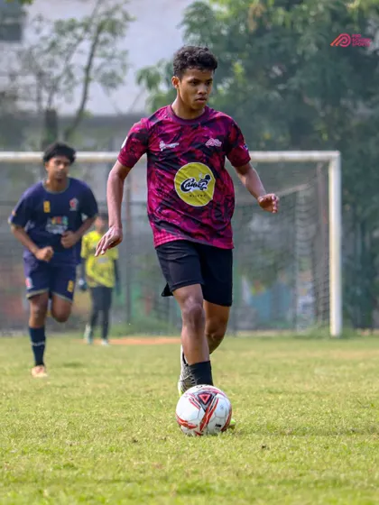 With eyes on the goal, our player advances the ball up the field during a crucial match.
