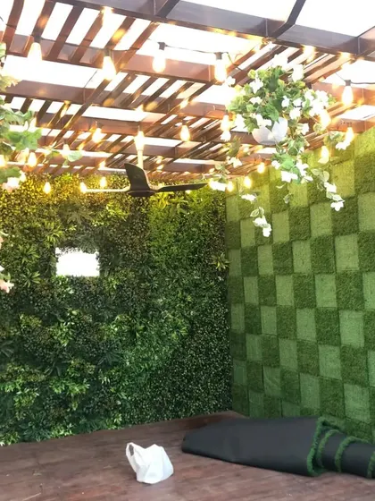 The full view of the pergola decoration. The checkerboard wall, a lush vertical garden, hanging plants, and warm lights all come together to create a magical outdoor room.