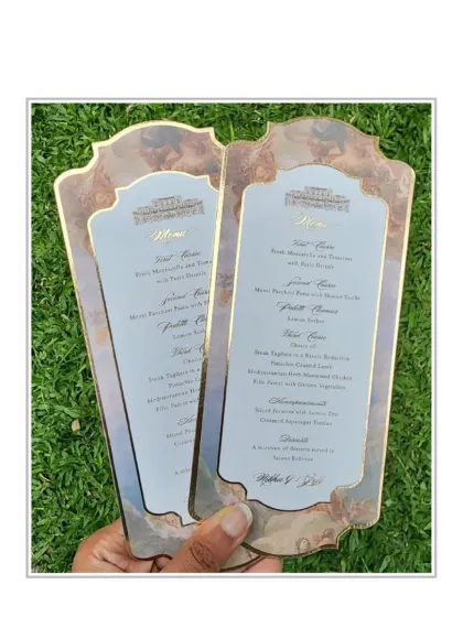 A closer look at the Rome-themed menu cards, held up to show the beautiful printing on iridescent paper, which gives the classic art a modern, ethereal glow.