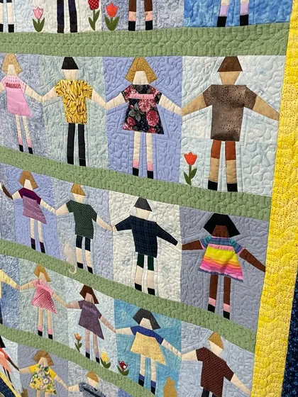 A detail shot of a "Paper Doll" quilt, where each doll has a unique fabric dress.